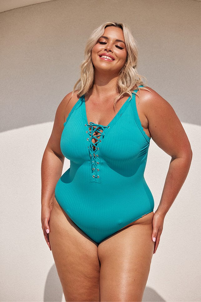 blonde model wears turquoise blue lace up one piece swimsuit