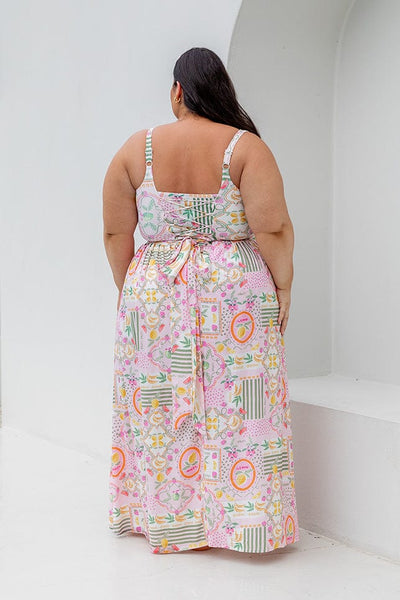 Back of model wearing high waisted maxi skirt with tie detail in fruit pattern for curve women