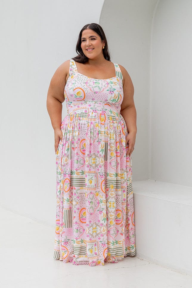 Brunette woman wearing plus size maxi skirt with pale pink base and multi coloured fruit print
