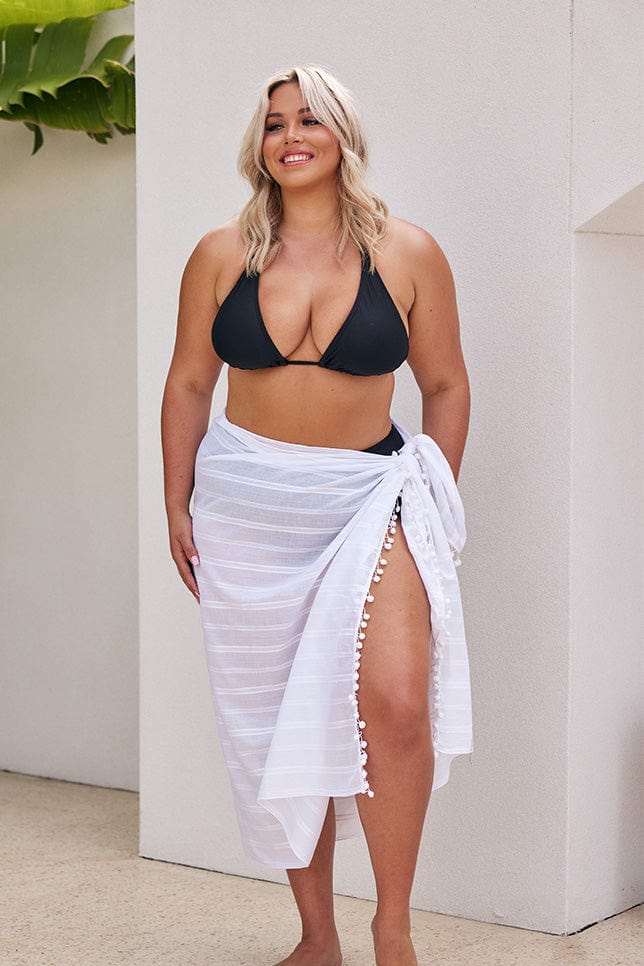 Blonde model wearing long white sarong over black bikini set
