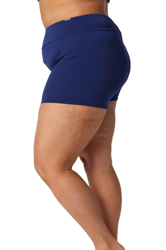 Curve woman standing in studio wearing navy boy leg shorts to swim in
