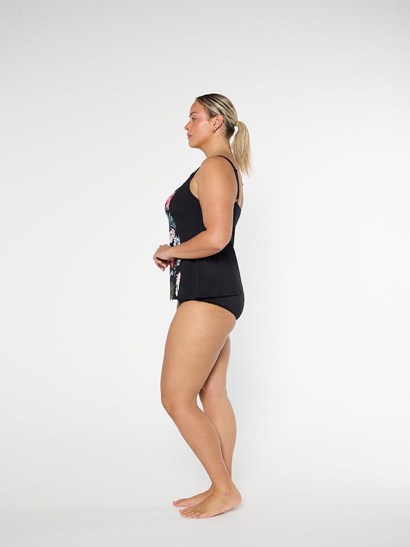 Woman wearing a black swimsuit with floral design on a white background