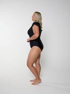Woman wearing a black swimsuit against a white background