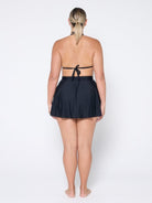 Person wearing a black halter top and skirt set on a white background