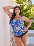 Brunette model wears flattering blue floral bandeau tankini with removable straps and shelf bra