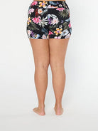 Woman wearing a black floral high-waisted bikini bottom on a white background