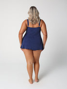 Person wearing a navy blue slip dress on a white background