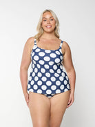 Blonde model shows tummy control swim bottom in navy and white polkadot pattern