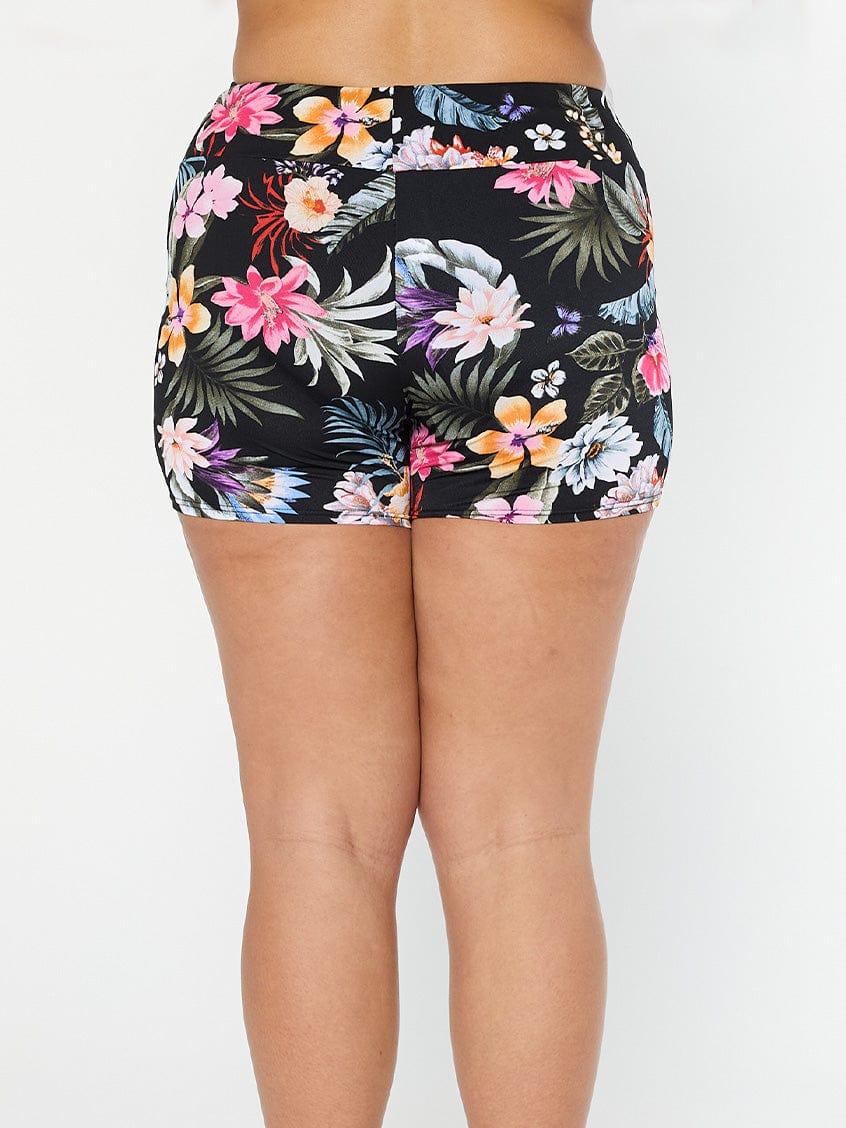 Model shows the back of black floral pool proof boyleg swim shorts with high-waist
