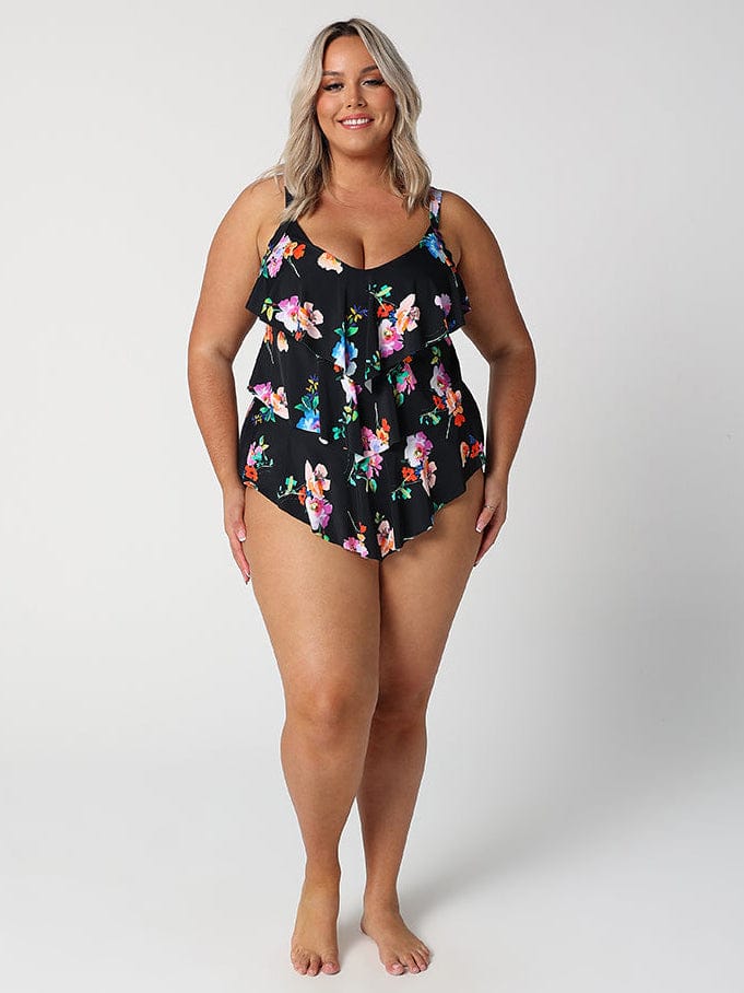 Woman wearing a black floral one-piece swimsuit on a white background