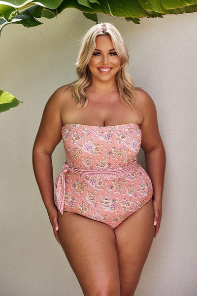 Blonde model wearing blush pink strapless one piece swimsuit