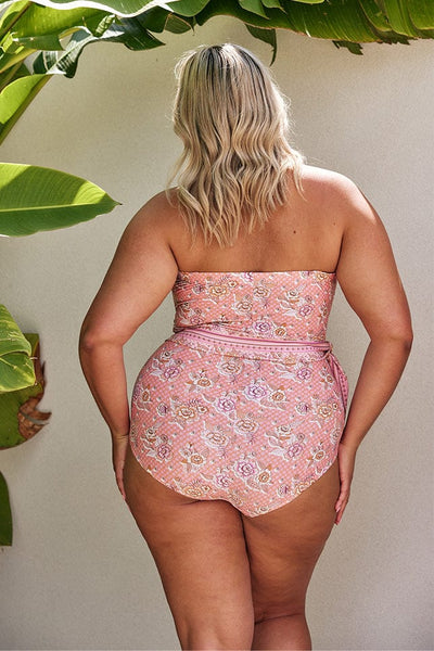 Blonde model showing back of pink strapless one piece with waist tie