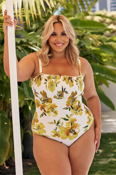 Blonde model wearing white and yellow floral swimsuit with shirred top