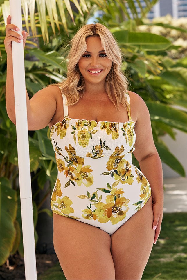 Blonde model wearing white and yellow floral swimsuit with shirred top