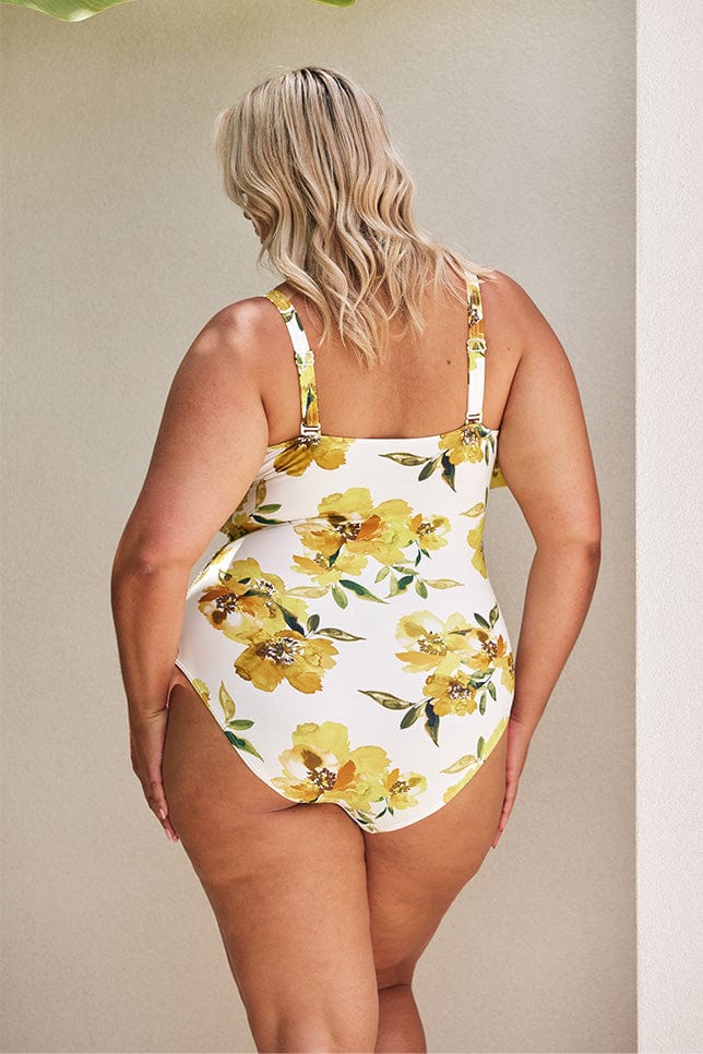 Blonde model showing back of white and yellow floral one piece
