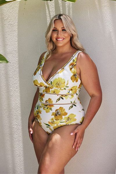 Blonde model wearing white and yellow floral v neck one piece swimsuit