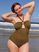 Woman wearing a green swimsuit on a beach with ocean waves in the background