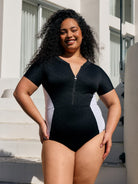 Model by pool wearing a zip front one piece with black and white panel detail