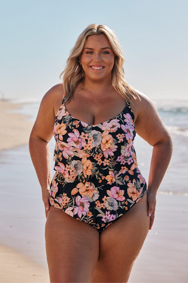 Blonde model wearing black and pink floral ruffled swimsuit