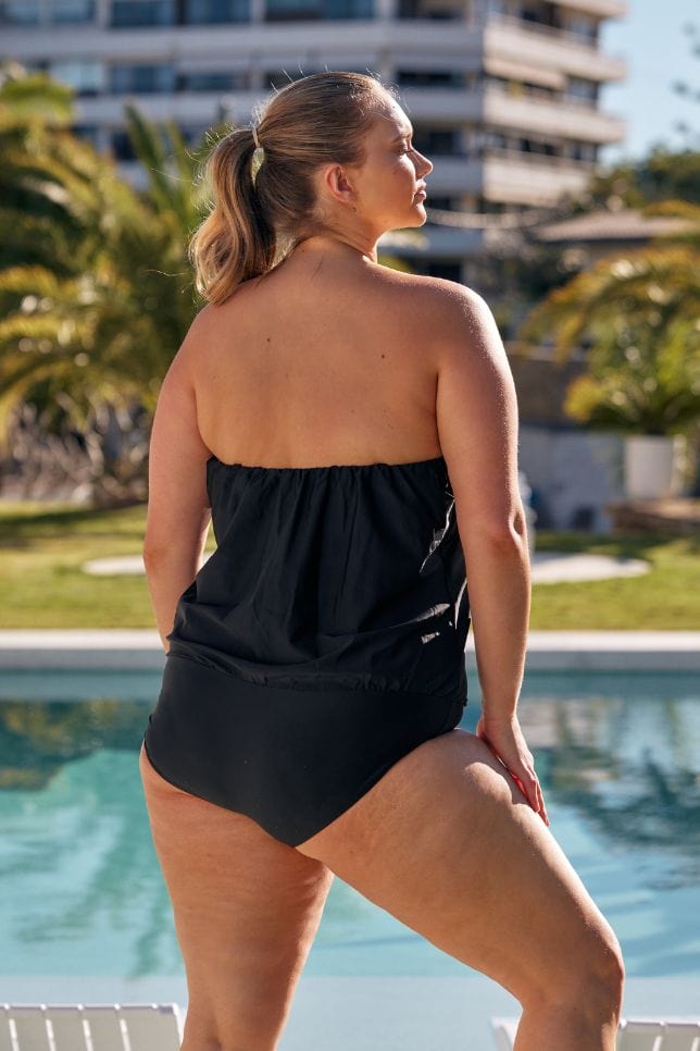 Blonde curve model by pool wearing black strapless plus size swimsuit with removable straps