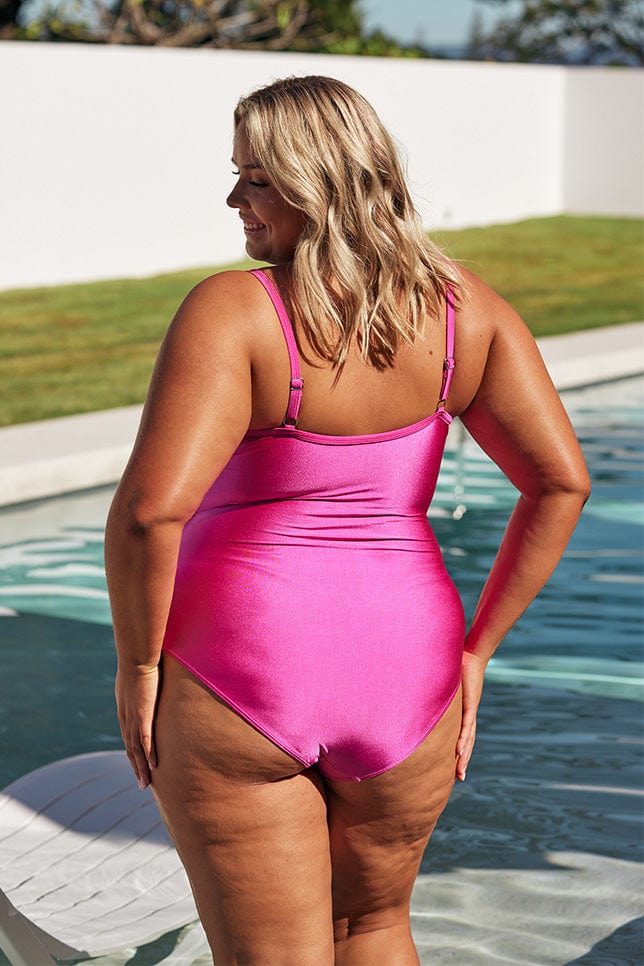Blonde model wears hot pink one piece swimsuit with adjustable straps