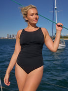 model wearing black high neck swimsuit on boat