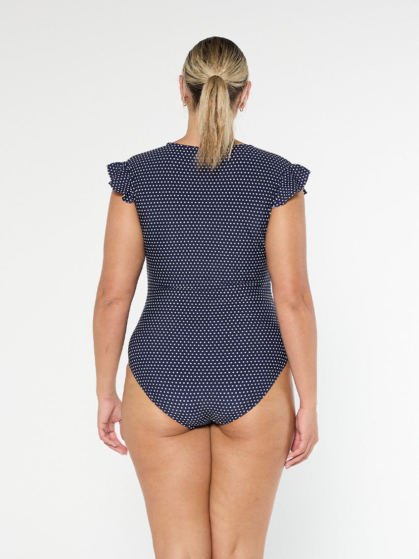 model showing back of navy polka dot frill sleeve one piece