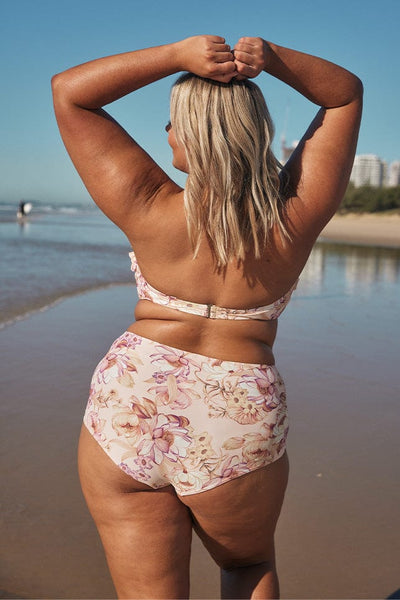 Blonde model showing back of light pink floral bikini on beach