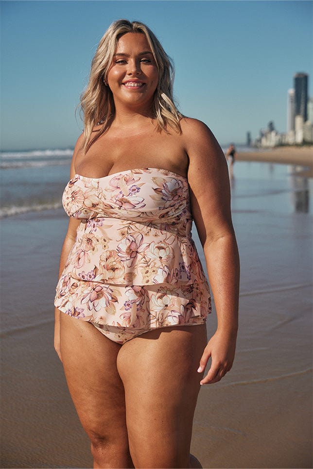 Blonde model wearing light pink tiered tankini at the beach