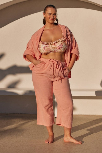 model wearing a musk pink crepe long length lounge wear set unbuttoned with a bikini top underneath