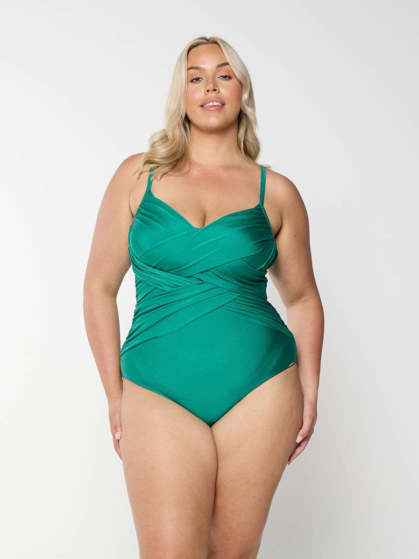 Blonde model in studio wearing a plus size one piece in metallic green with ruching 