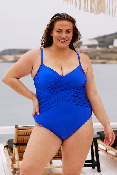 Brunette model wearing metallic blue criss cross swimsuit