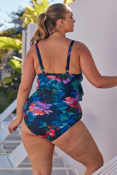 back of model wearing a navy based floral one piece with adjustable back straps