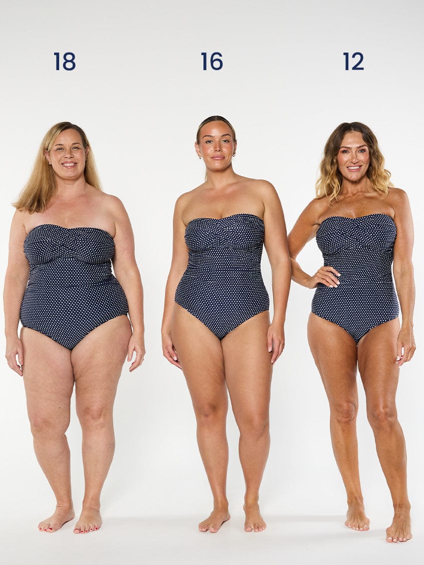 three models wearing navy and white dots bandeau one piece