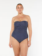 model wearing navy polka dot women's strapless one piece