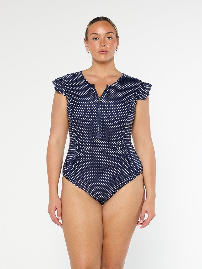model wearing navy and white dots frill sleeve zip front one piece