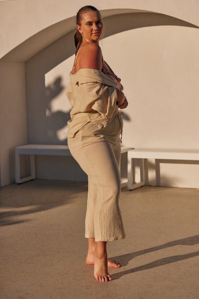 side profile of model wearing a taupe cheesecloth shirt with matching pants