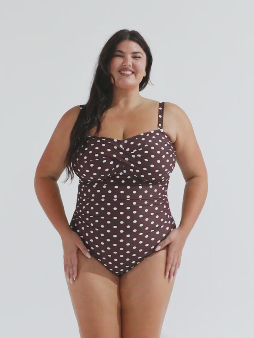 Model in studio wearing a chocolate spot bandeau one piece with removable straps