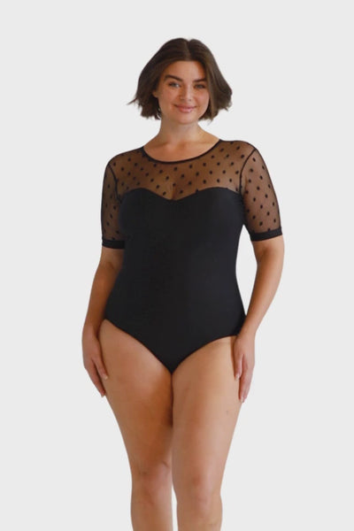 Blonde curve model wearing black one piece with mesh polkadot detail short sleeve and black sweetheart neckline