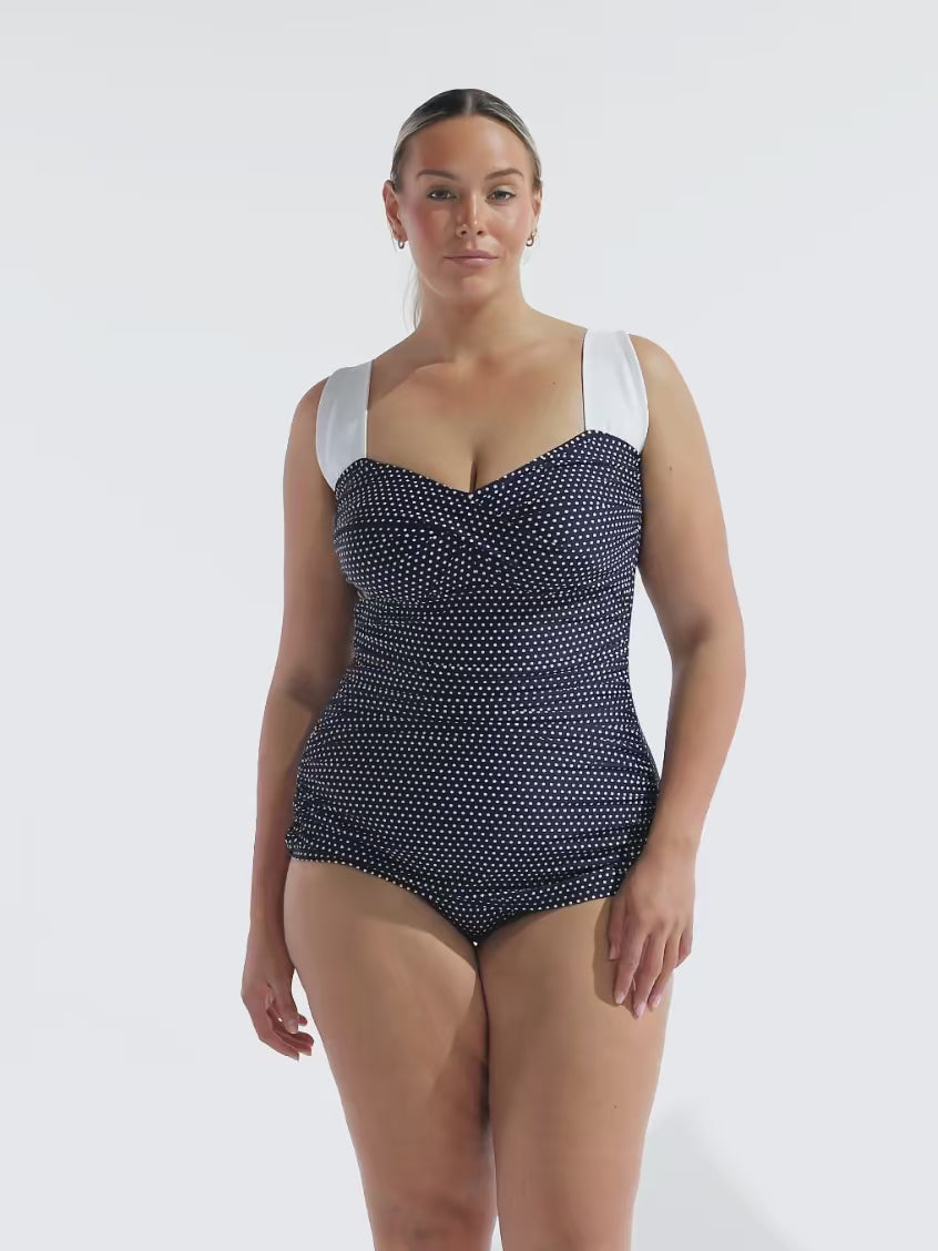 model wearing navy and white dots retro inspired one piece
