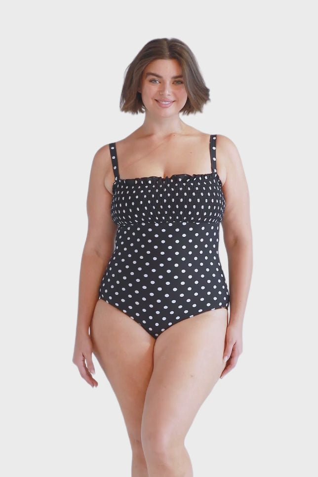 Brunette plus size model wears black and white spotty shirred bandeau one piece with removable straps