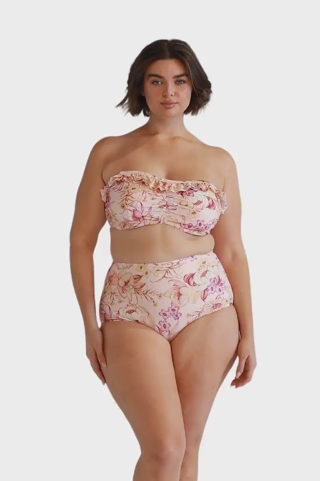 Brunette model wearing pink strapless bikini top with ruffle for curve women