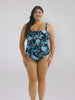 Brunette model in studio wearing tank one piece in blue and black floral 