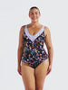 A woman modeling a one-piece swimsuit with a dark navy floral print and a light blue crochet V-neck trim.