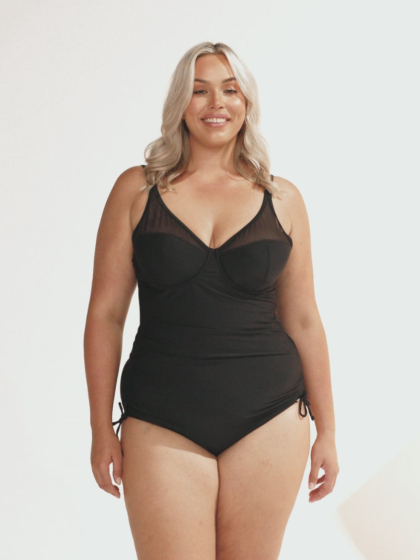 Blonde curvy woman in studio wearing one piece with mesh detail on bust