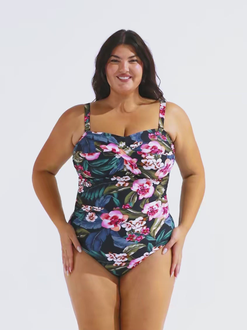 Model in studio wearing a twist front bandeau one piece with removable and adjustable straps in floral print