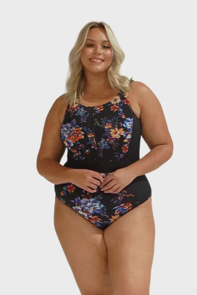 Blonde model in studio wearing a chlorine resistant one piece with zip front and high neck in orange and blue print