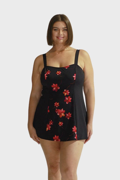 Brunette curve model wearing chlorine resistant wide strap swim dress with pink flowers 