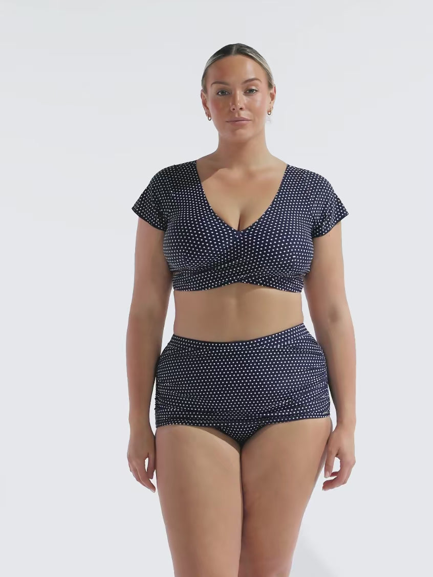 model wearing navy polka dot wrap crop top and skirted pant