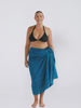 Blonde model in studio wearing a pom pom sarong in teal colour
